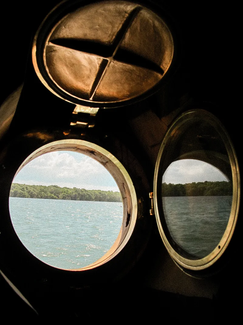 Brass portholes in a cabin aboard Waow 2, looking out to the sea.
