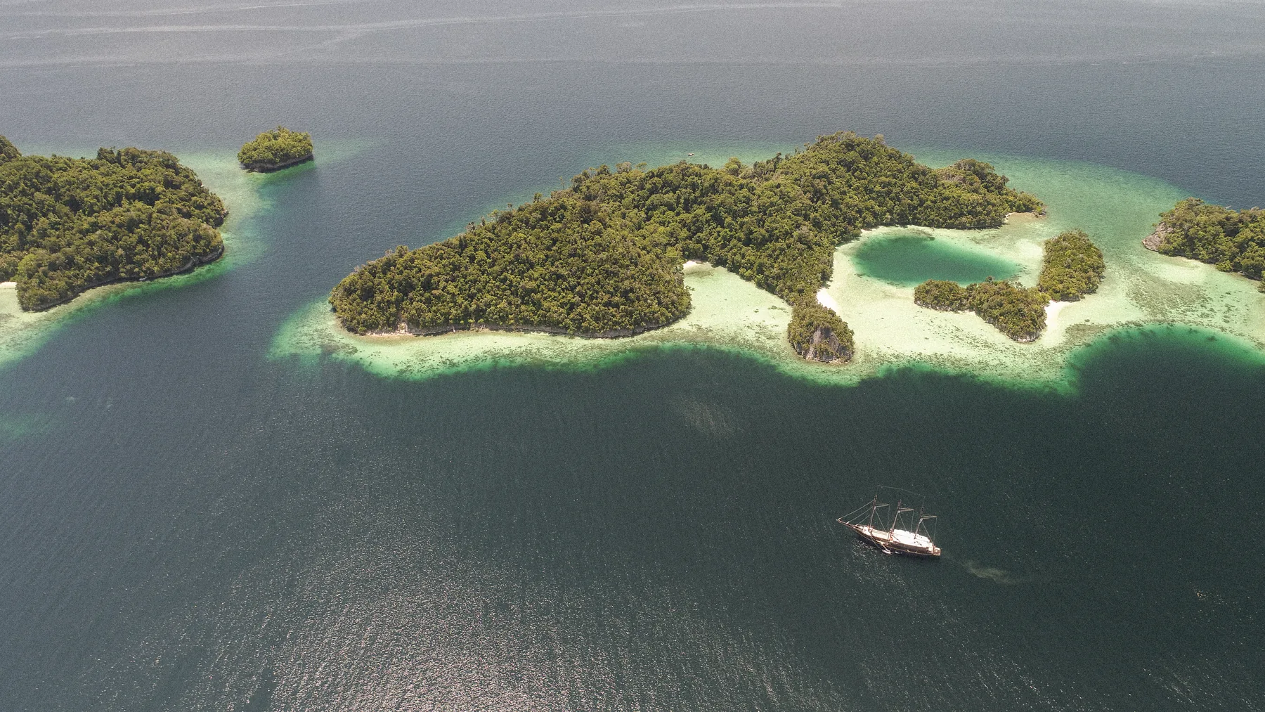 Aerial view of forested islands and turquoise water.
