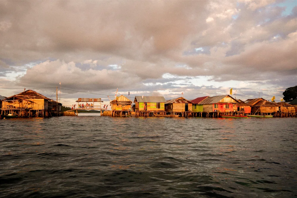 Stilt houses over the water at sunset.