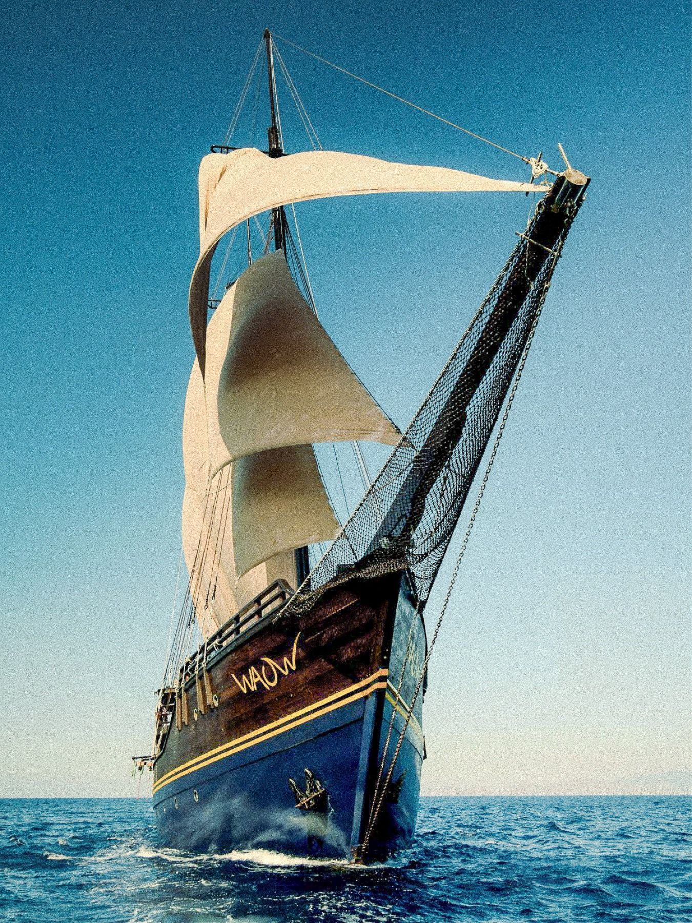 Waow 2's bow rising under sail, rigging against a clear sky.